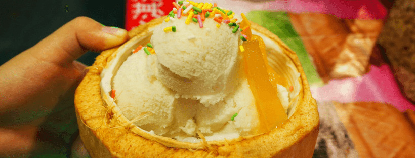 A fresh coconut filled with coconut ice cream and topped with sprinkles, Thai street food.