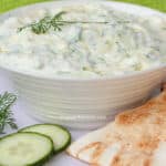 Homemade tzatziki with dill, pita bread, and cucumbers.