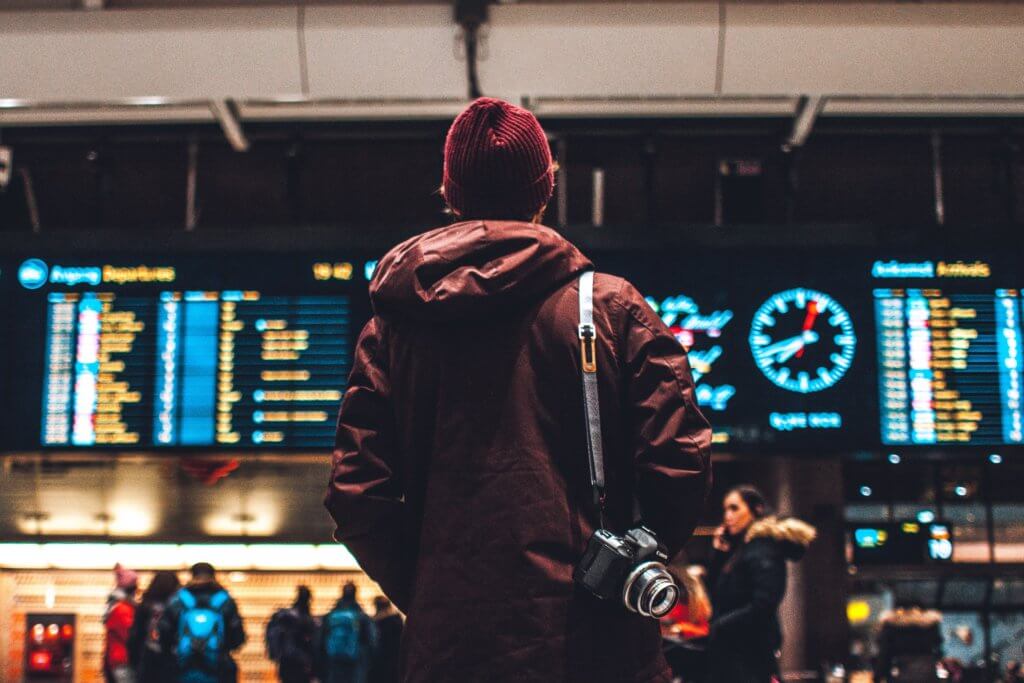 Žmogus, stovintis prieš tvarkaraštį lentoje oro uoste