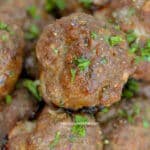 Italian meatballs piled in a serving dish garnished with parsley.