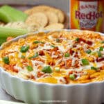 Frankerne buffalo chicken dip i en serveringsskål ved siden selleri, ritz kiks, og andre vandstære.