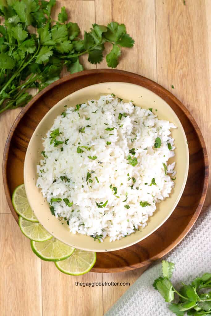 An overhead shot of cilantro lime rice surrounded by lime and cilantro.