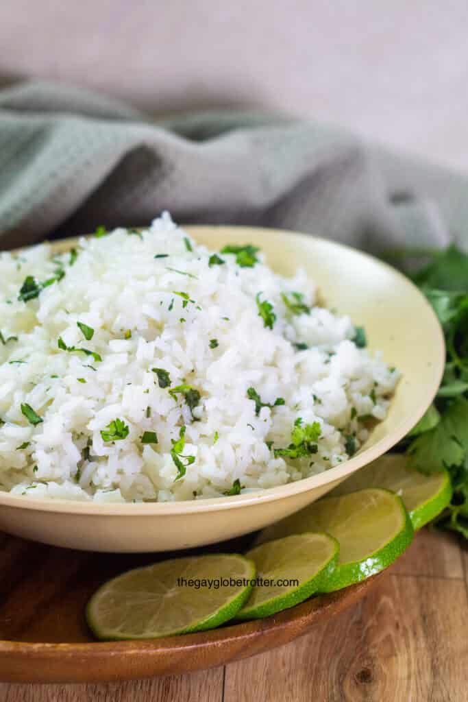 A serving bowl of cilantro lime rice surrounded by lime wedges.