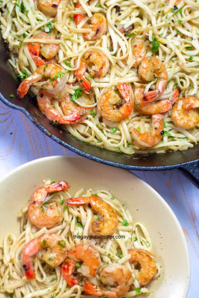 A bowl of shrimp scampi next to a pan full of more scampi.