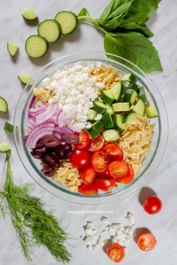 A bowl of Greek orzo pasta salad ready to be tossed.