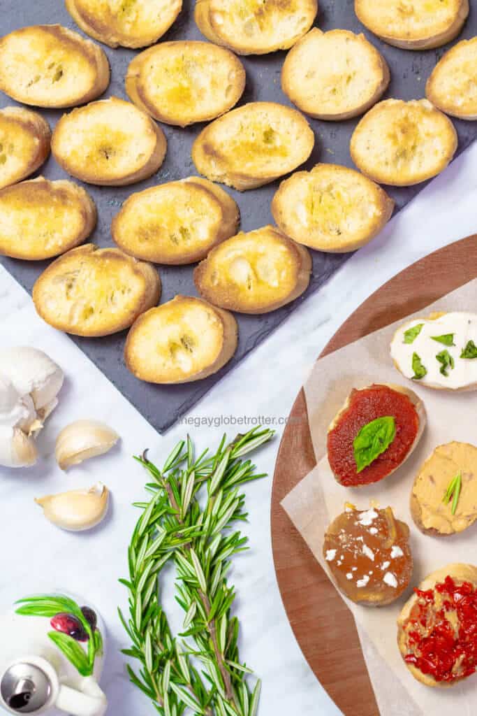 A flatlay of homemade crostini next to crostini pieces with various toppings.