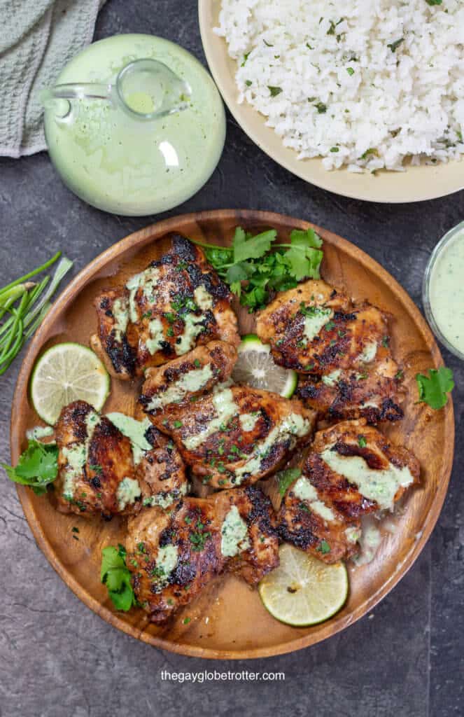 An overhead shot of Peruvian chicken on a wooden serving plate with aji verde on it. 