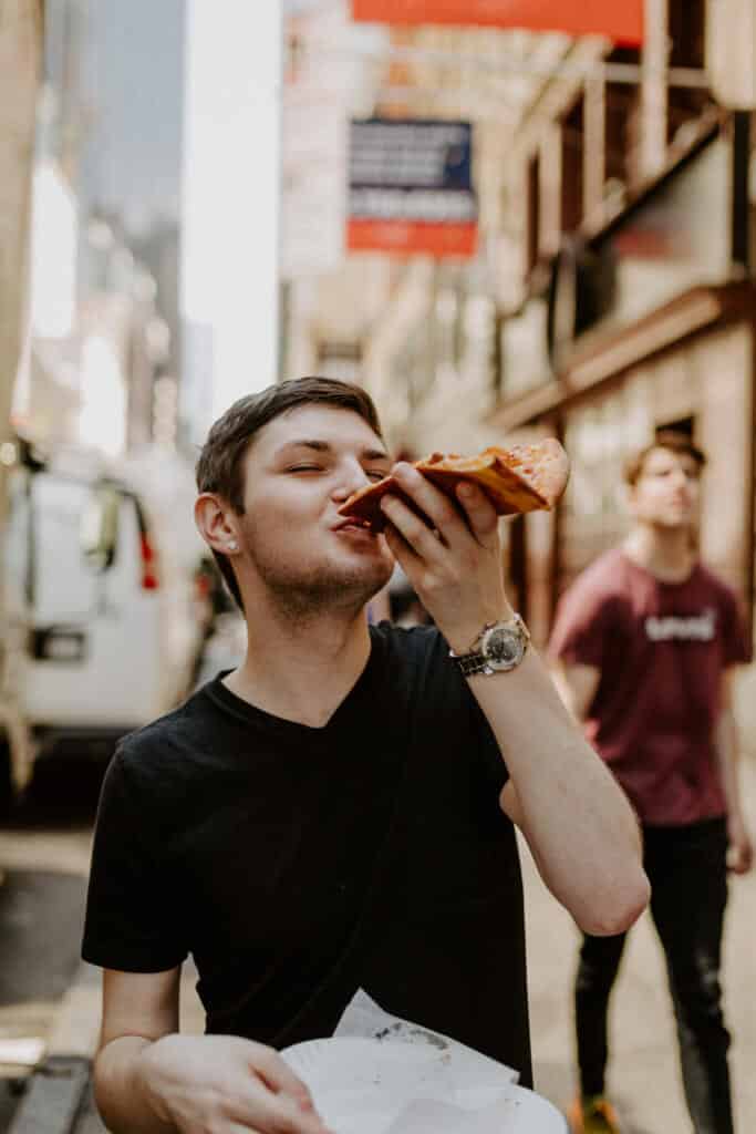 A man eating pizza in Manhattan, New York City.