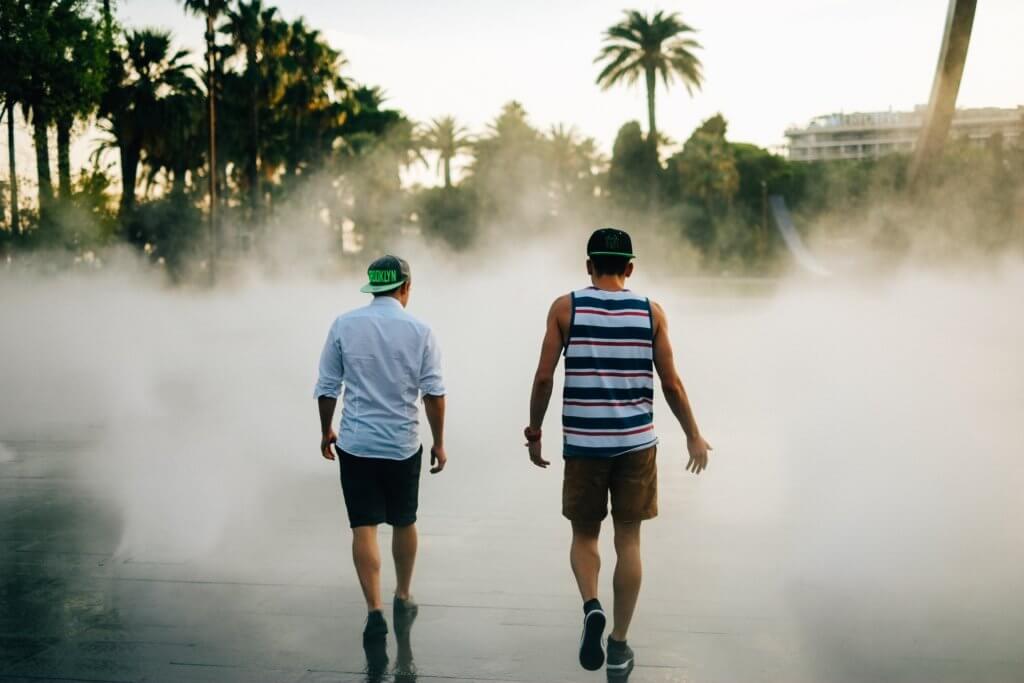 Two men walking towards fountain in tropics