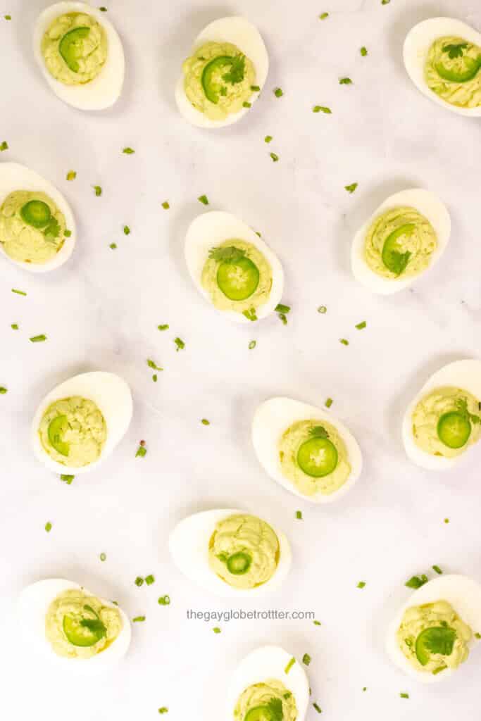 Avocado deviled eggs scattered on a marble surface.