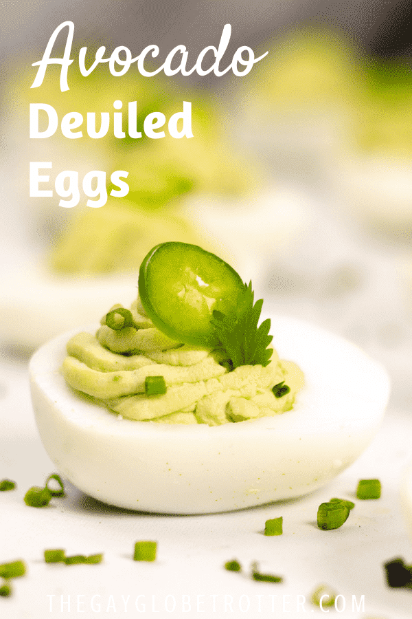 A closeup of a deviled egg with text overlay that says "Avocado Deviled Eggs".