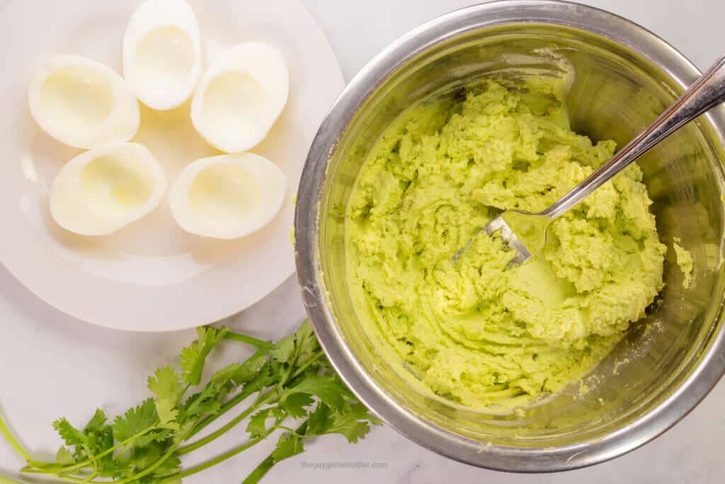 A bowl of avocado yolk mixture next to egg whites.