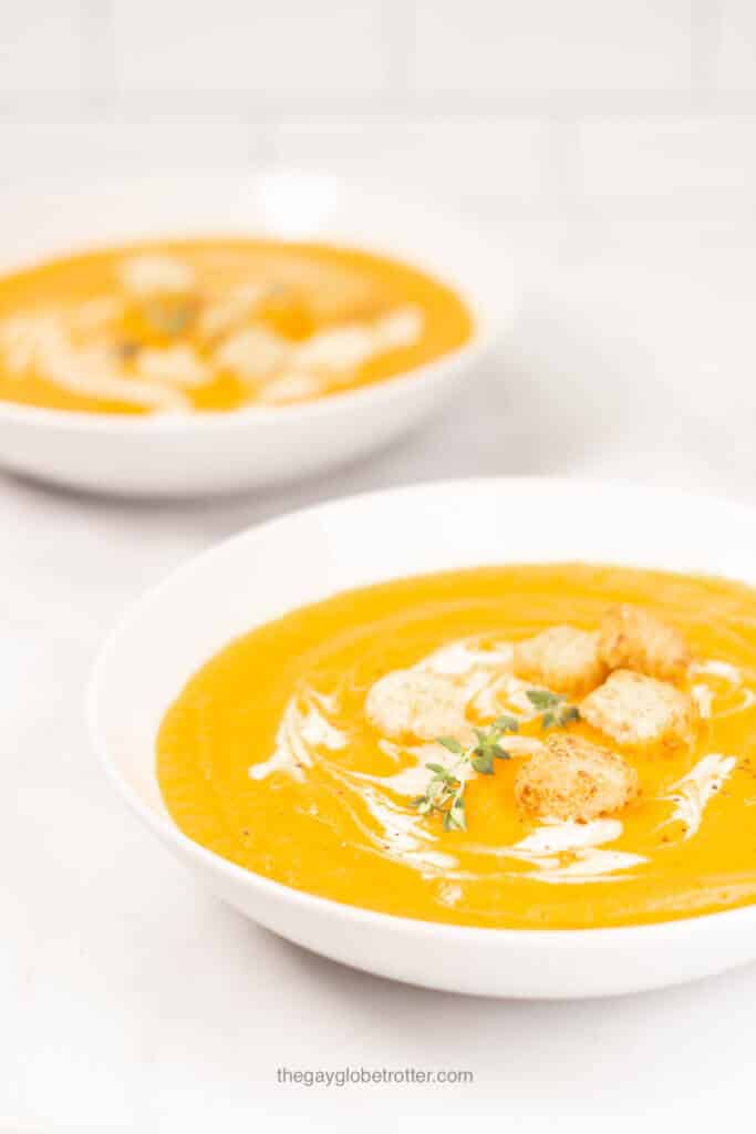 A bowl of creamy carrot soup being served.