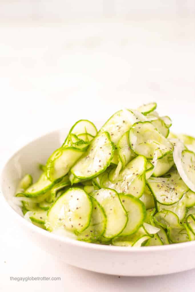 A serving bowl of cucumber vinegar salad with black pepper.