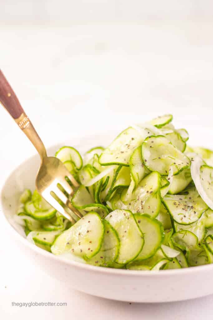 A fork digging into a bowl of fresh cucumber vinegar salad.