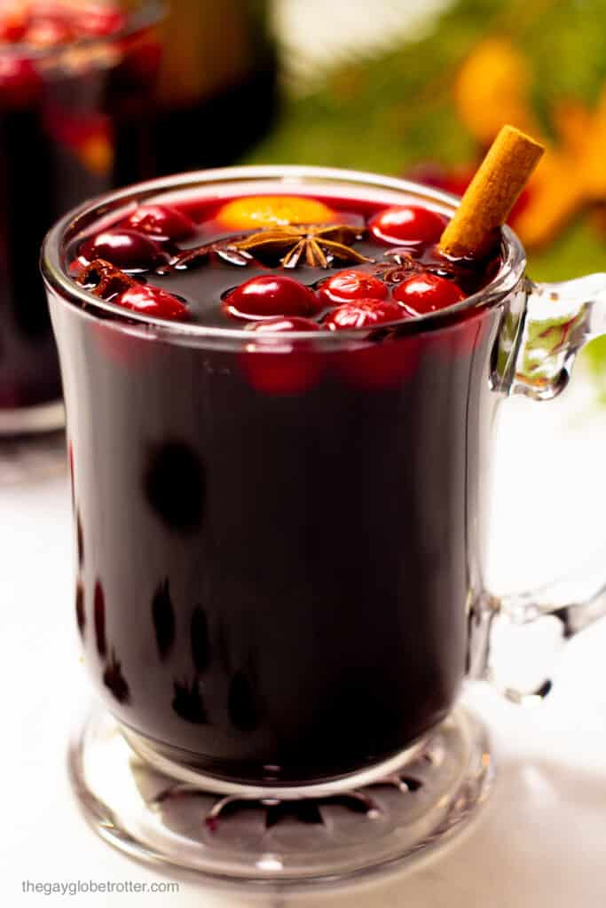 A big glass of slow cooker mulled wine with fresh cranberries and spices.