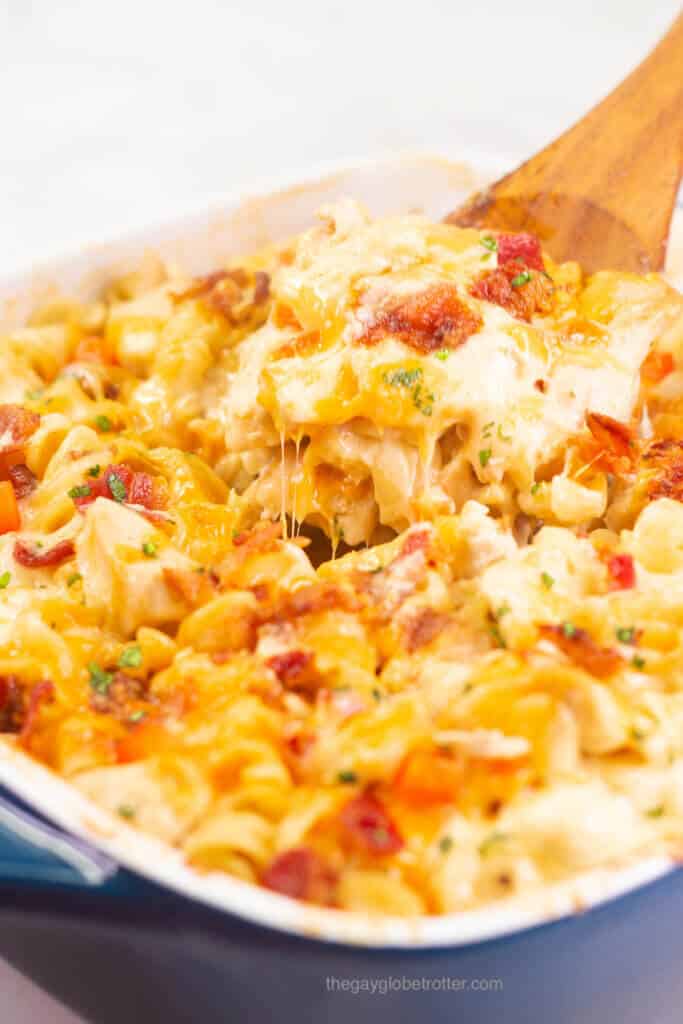 A casserole dish of chicken bacon ranch casserole being served with a wooden spoon.