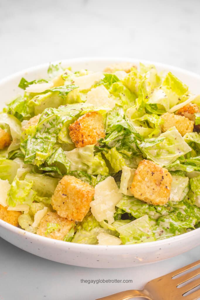 A close up of caesar salad with croutons, pepper, and dressing.