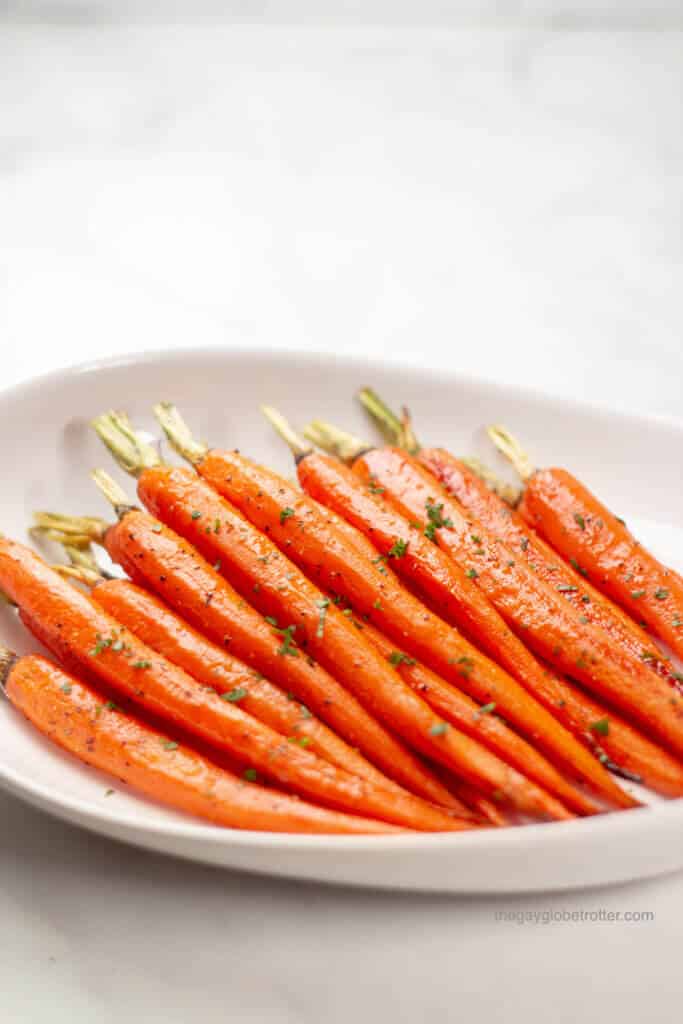 Honey glazed carrots garnished with parsley in a serving dish.