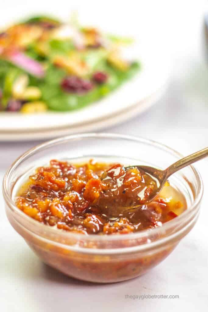 A bowl of warm bacon dressing with a small spoon.