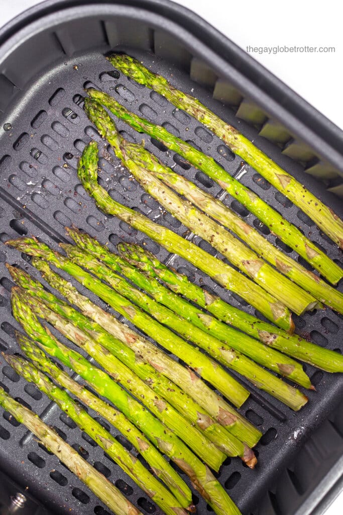 An air fryer basket full of air fryer asparagus ready to serve.