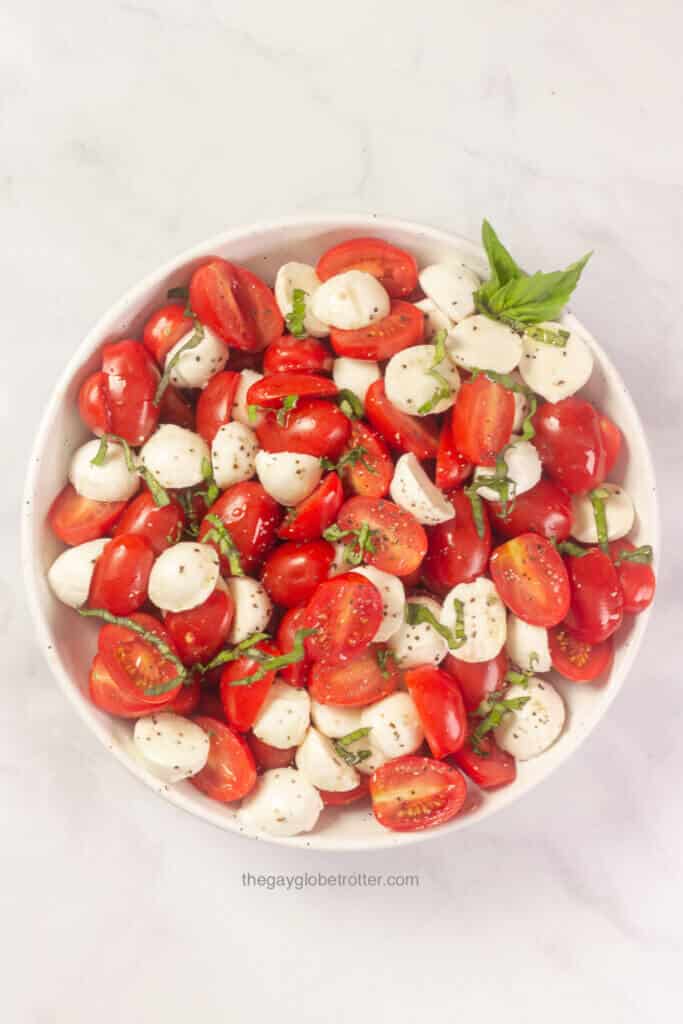 A bowl of caprese salad with fresh basil garnish.