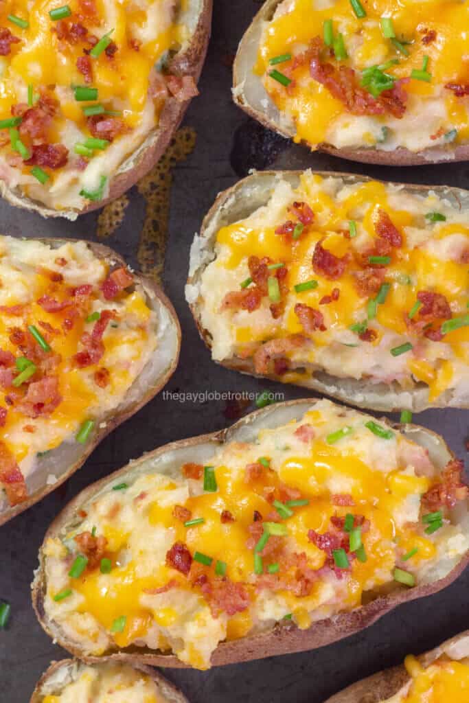 Twice baked potatoes arranged on a baking sheet garnished with chives.