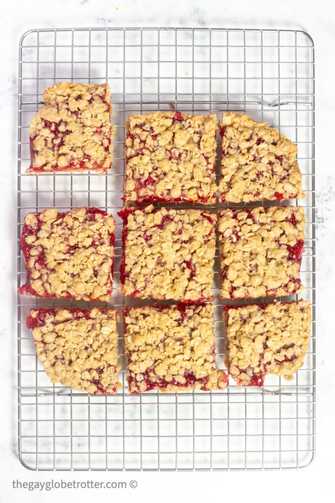 Raspberry oatmeal bars cut into squares on a cooling rack.