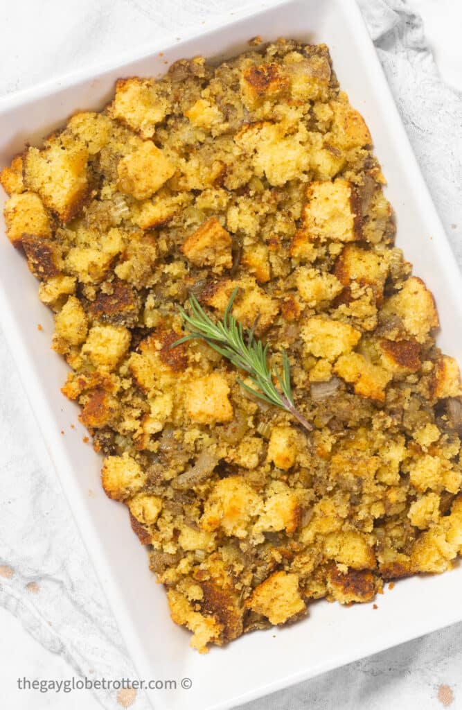 Cornbread stuffing in a serving dish garnished with rosemary.