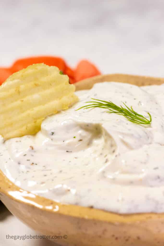 Dill dip with a chip being dipped into it.