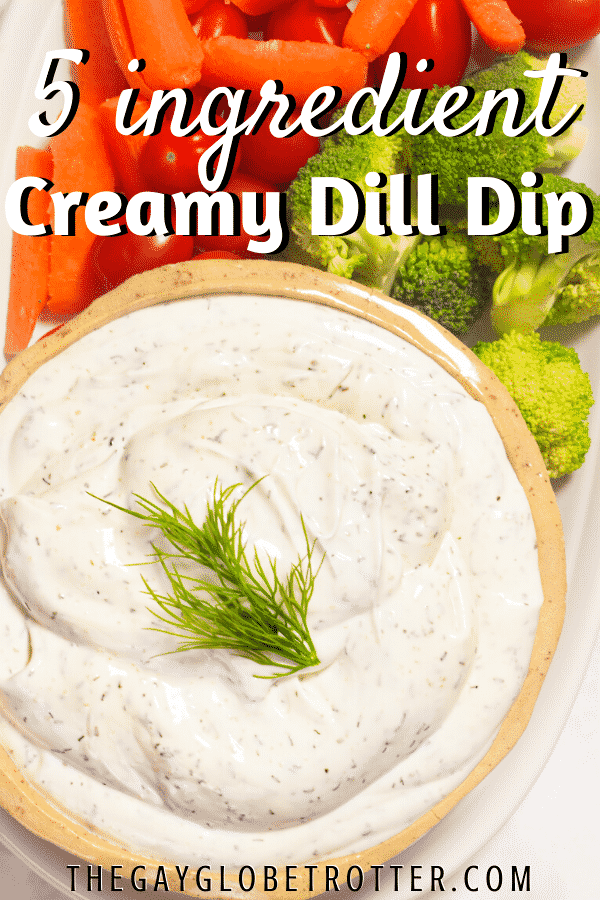 Dill dip garnished with dill next to vegetables.