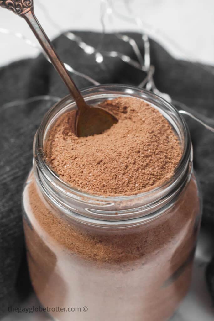 Hot chocolate mix in a glass jar with a spoon.