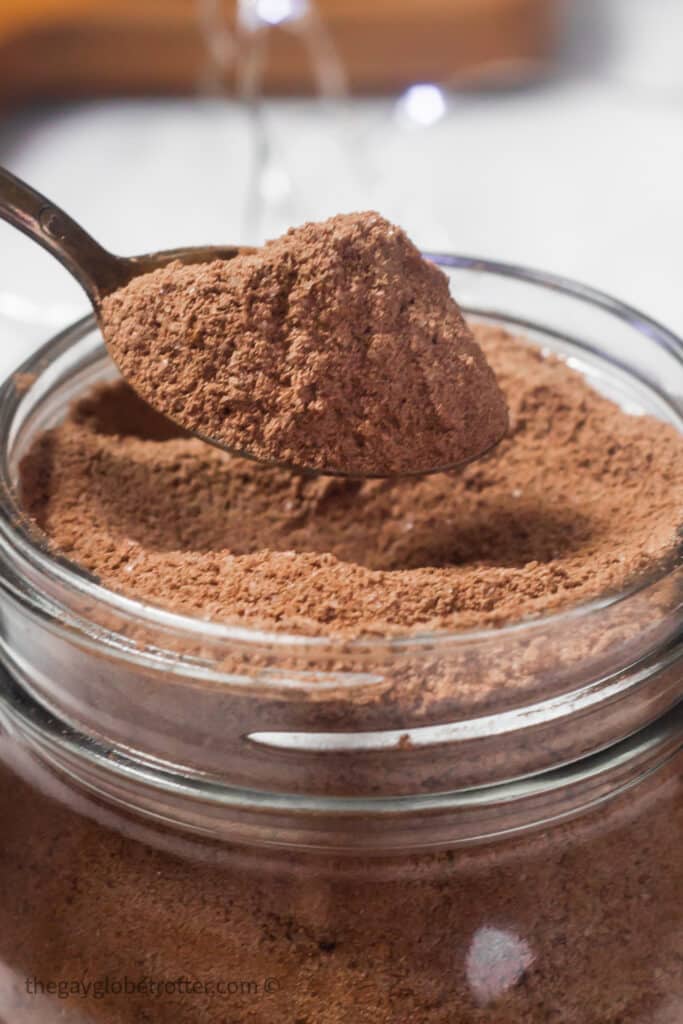 A spoon scooping homemade hot chocolate mix out of a jar.