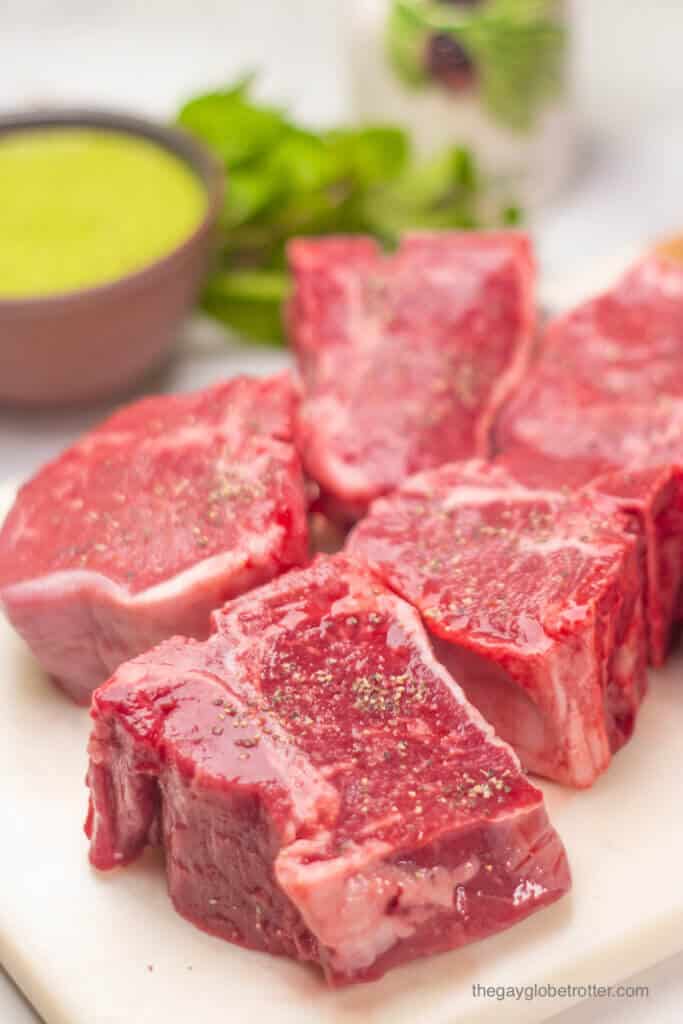 Lamb loin chops with salt and pepper on a cutting board.