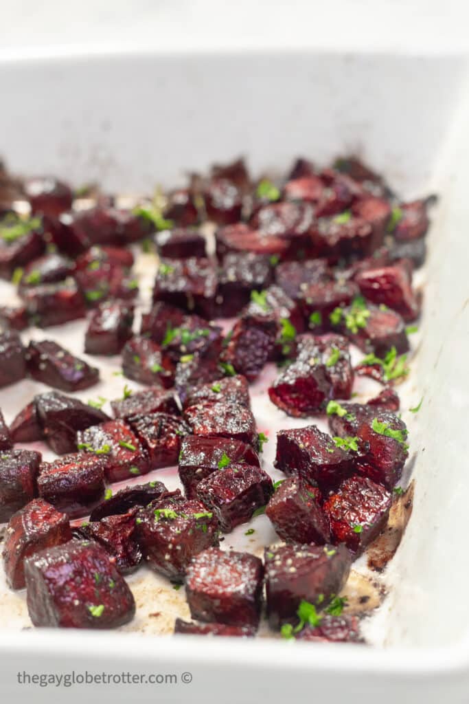 Oven roasted beets topped with parsley in a baking dish.