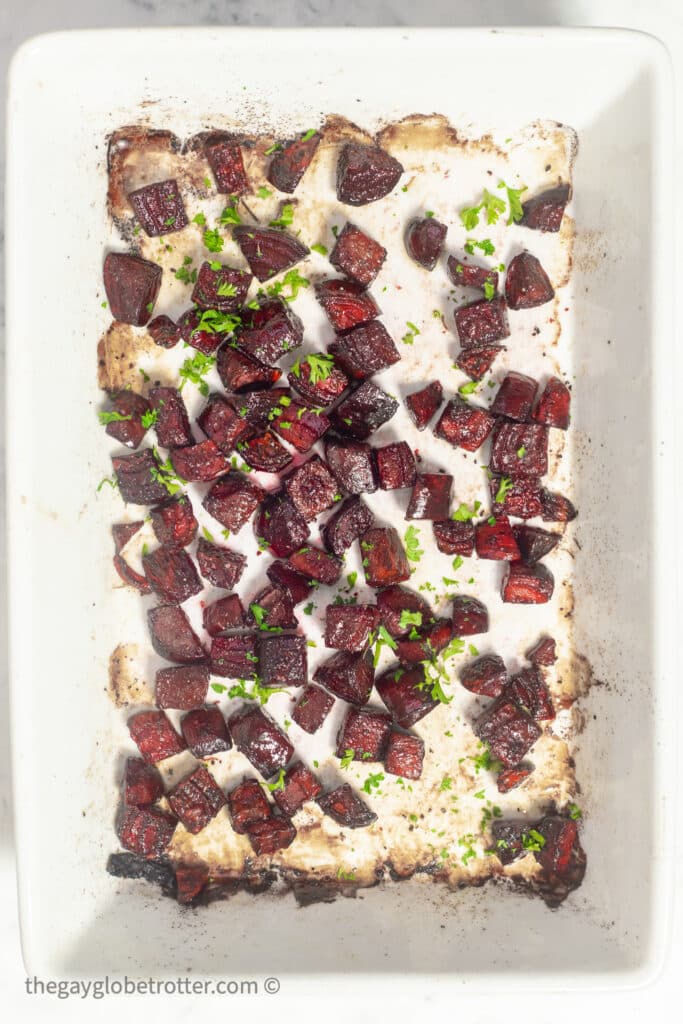 Roasted beets in a baking dish topped with parsley.