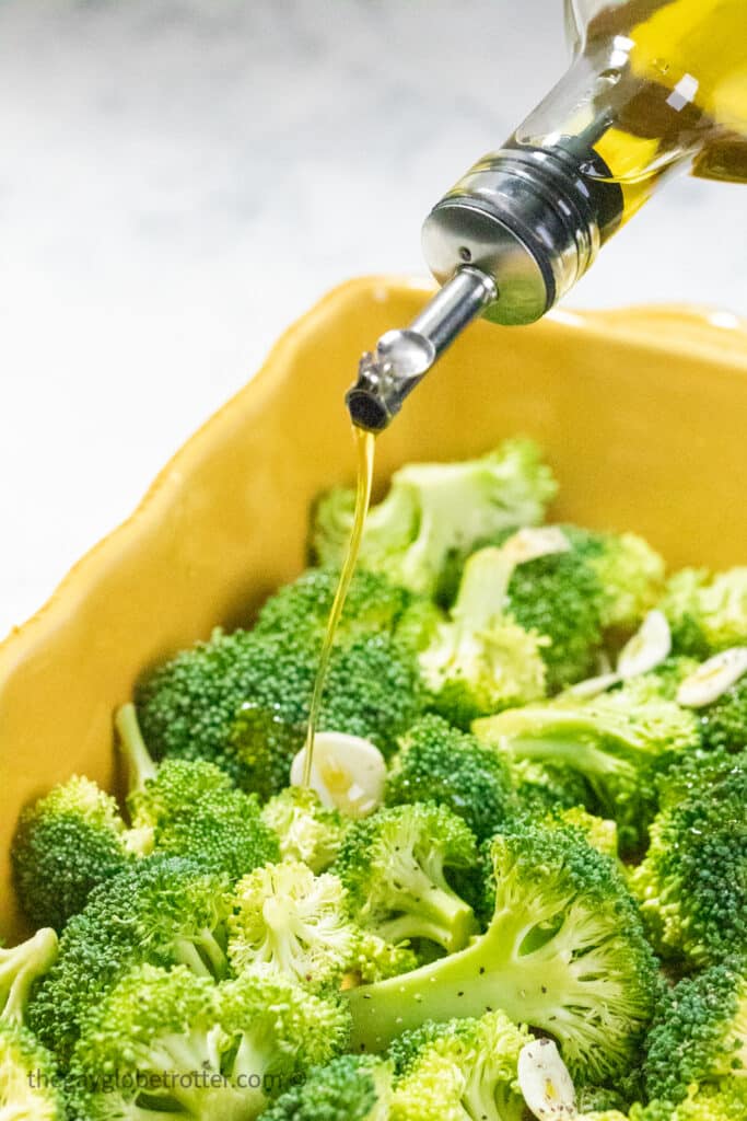 Olive oil being drizzled on broccoli.