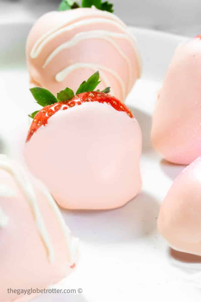 Pink chocolate covered strawberries on a serving plate.