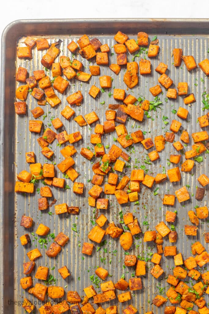 Oven roasted sweet potatoes on a baking sheet with parsley.