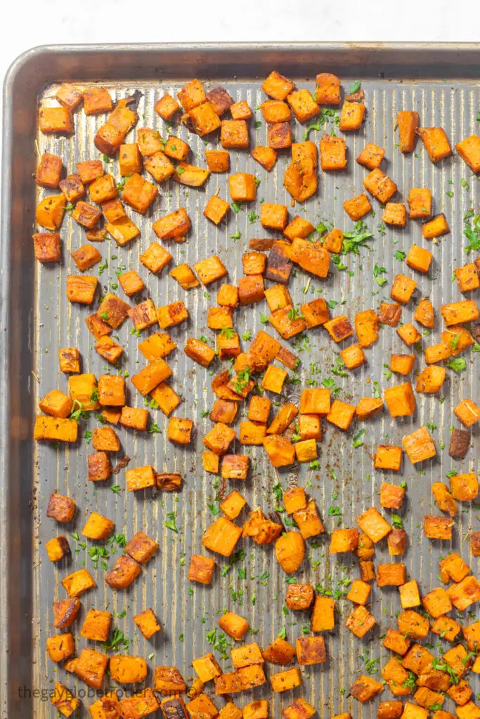 Oven roasted sweet potatoes on a baking sheet with parsley.