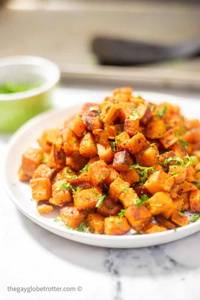 Roasted sweet potatoes on a plate with fresh parsley.