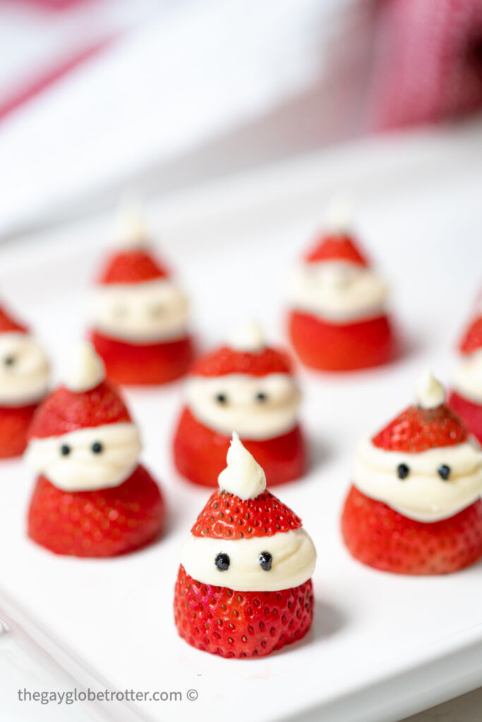 A plate of strawberry santas piped with vanilla icing.