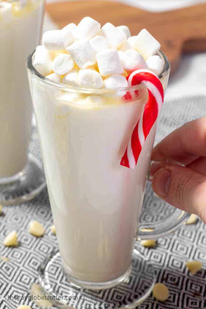 A cup of white hot chocolate with a candy cane.
