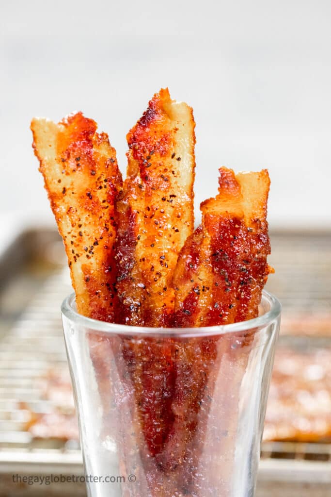 Candied bacon in a clear cup.