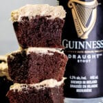 Guinness brownies with icing stacked next to a can of beer.