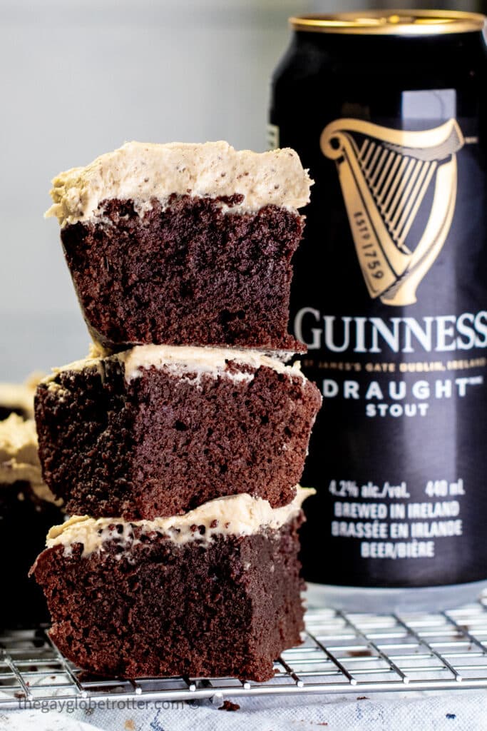 Guinness brownies with icing stacked next to a can of beer.