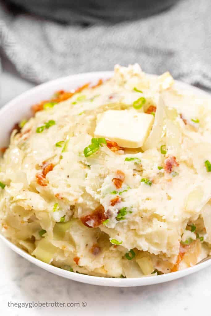 Colcannon in a serving dish topped with butter.