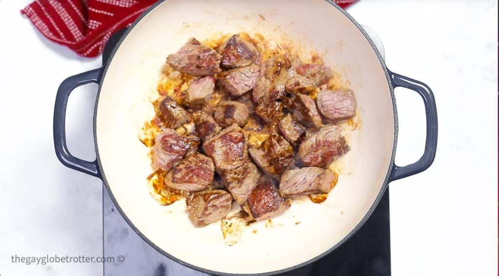 Beef being seared in a dutch oven.