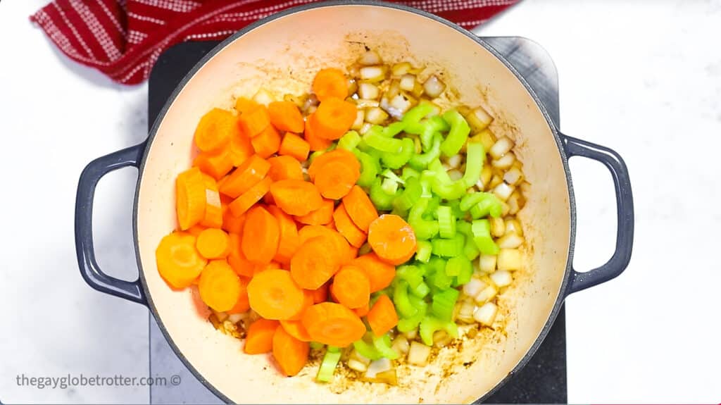 Celery, carrots, and onions in a pot.