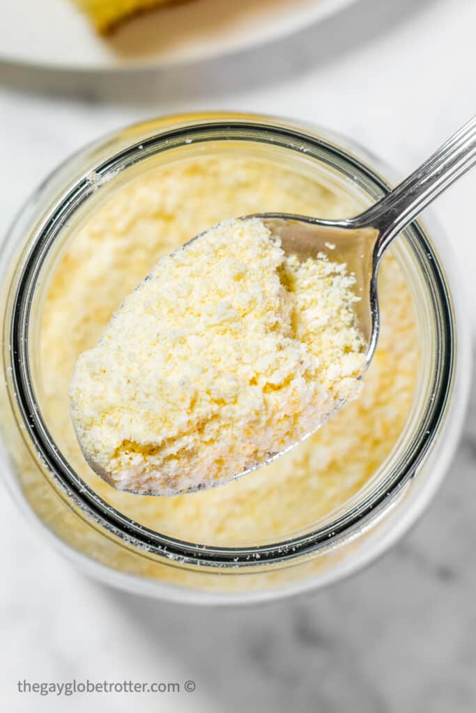 A spoon moving some jiffy corn muffin mix from a jar.